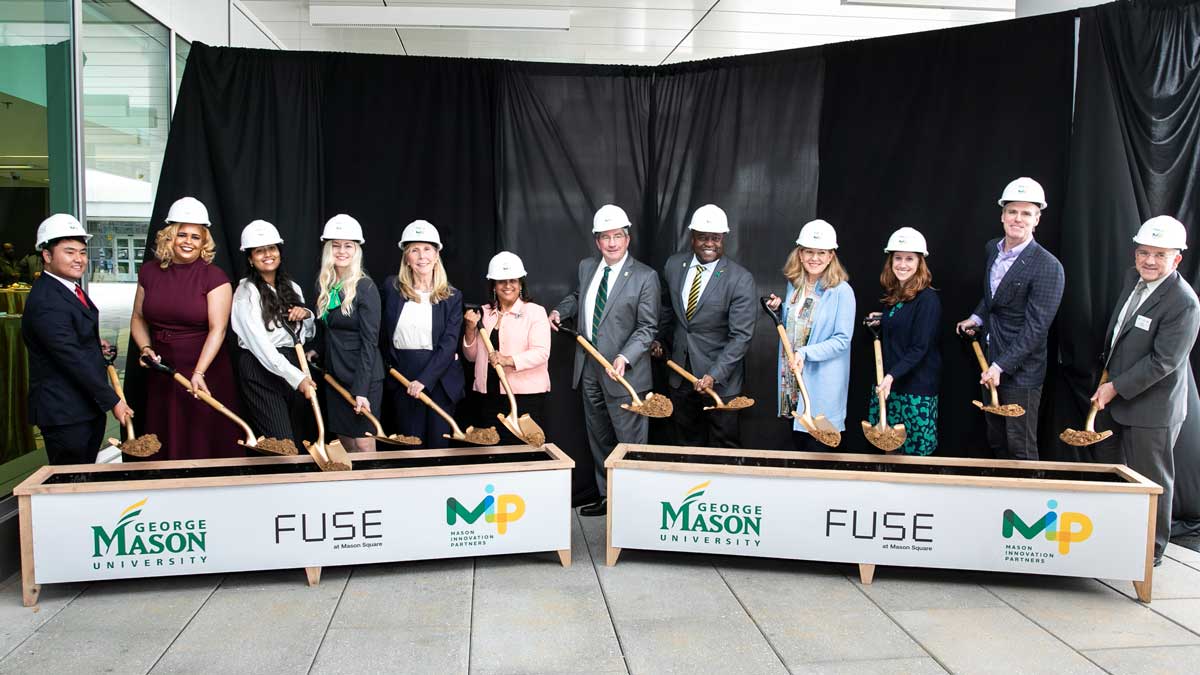 Mason leadership and students participate in ceremonial groundbreaking. Pictured are men and women in business attire, hard hats, and holding shovels. 
